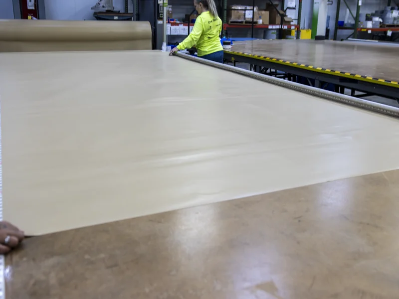Integra worker rolling Tan Aegis fabric on production floor — hands-on manufacturing